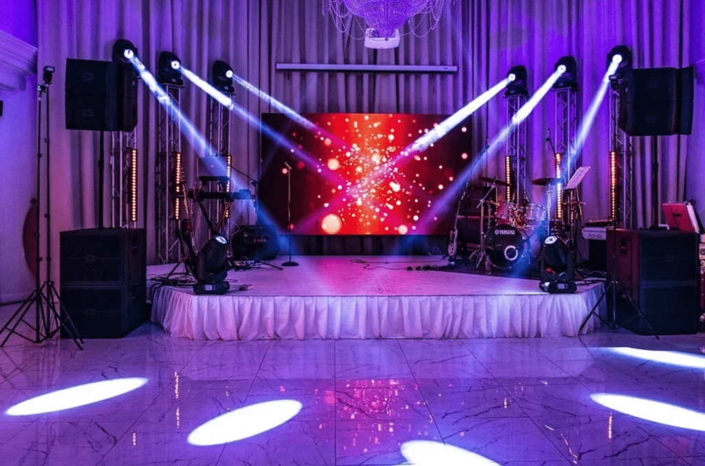 Stage with LED screen, dynamic lighting, and sound system for an indoor event setup in Calgary by Easy Event Rental